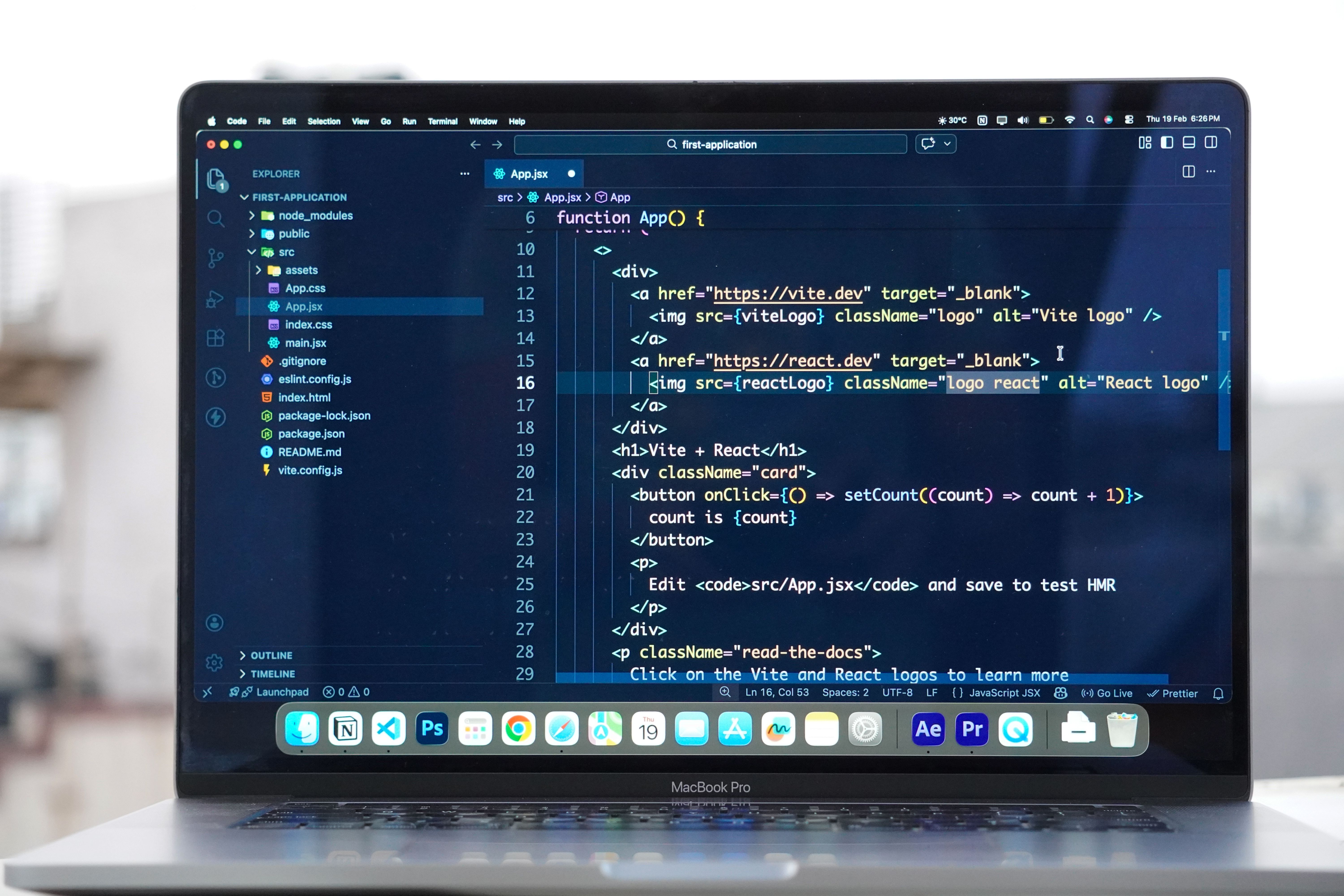 MacBook on a desk with a code editor and a web application project on screen